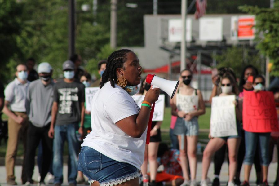 NO+JUSTICE+NO+PEACE+Speaking+on+a+megaphone+to+a+listening+crowd%2C+Kayla+Prowell%2C+class+of+%E2%80%9819%2C+recites+a+poem+during+the+protest+that+occurred+June+5.+Kayla+also+later+helped+plan+a+second+protest+at+the+town+hall.+Munster+saw+a+surge+of+students%2C+graduates+and+adult+support+in+response+to+the+resurgence+of+Black+Lives+Matter+this+year%2C+paralleling+the+peaceful+protests+that+have+been+sparked+throughout+the+nation%2C+%E2%80%9CWe%E2%80%99re+tired+of+having+to+do+this.+We%E2%80%99re+tired+of+having+to+fight+for+our+rights+over+and+over+and+over+again.+We+fought+for+them+300+years+ago%2C+we+fought+for+them+100+years+ago%2C+we+fought+for+them+60+and+50+years+ago.+We%E2%80%99re+always+fighting%2C+and+I+think+that+we%E2%80%99re+tired+of+being+our+own+advocates.+We%E2%80%99re+tired+of+people+not+being+tired+of+being+racist.