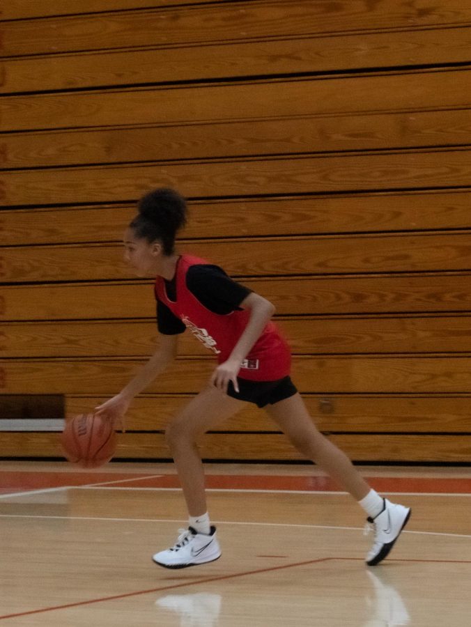 Dribbling the ball down the court, Nina Garner, freshman, in attempt to score a point during drills.
