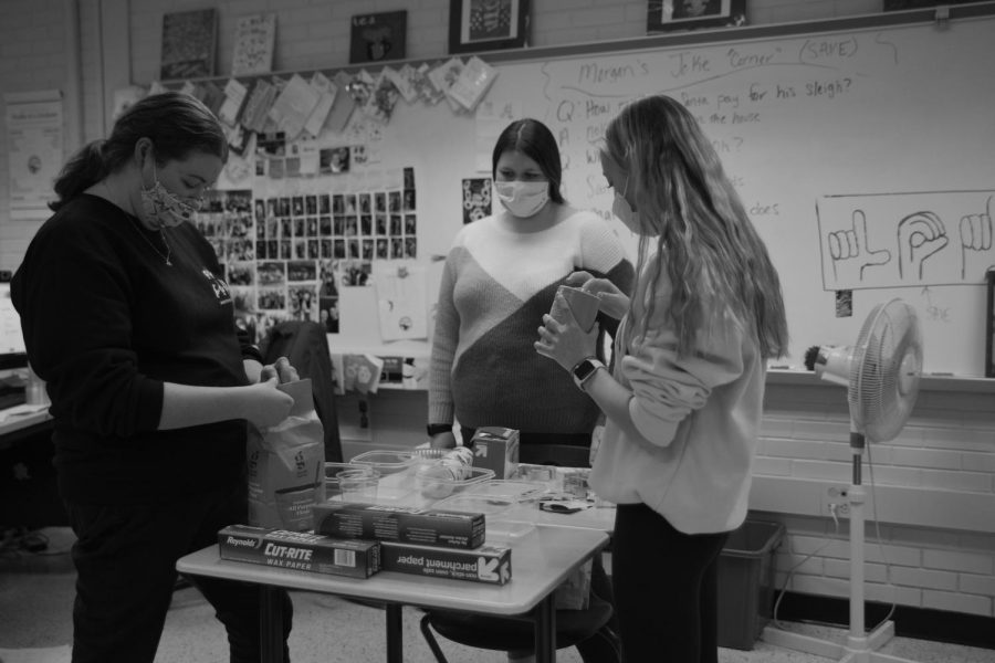MOLDING MEMORIES Setting up supplies to mix salt dough, Ms. Hannah Fus, Caityln Klos, senior, and Jilli Childs, junior, lead the ASL club in making ornaments for their Dec. 14 meeting. 