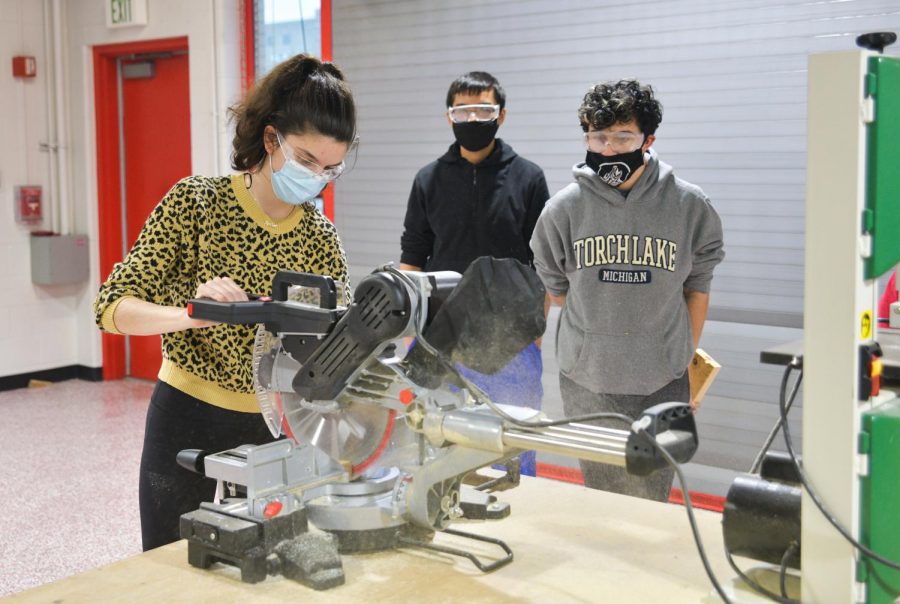 CAUTION Training students how to use the circular saw, Amelia Konstantinopoulos, senior, teaches equipment safety. Amelia has been helping Robotics members get their training certification for the Fab Lab. 
