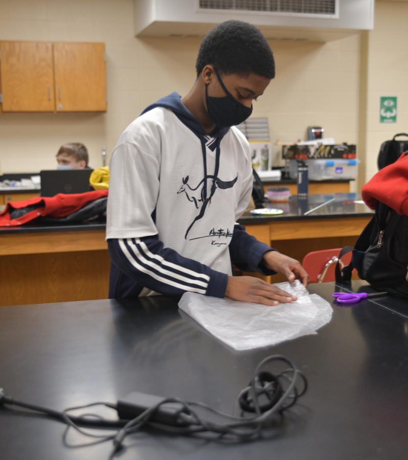 TAKING A CHANCE Building a rocket parachute to propel a pingpong ball in the air, Femi Ololade, sophomore, works on his Science Olympiad project.