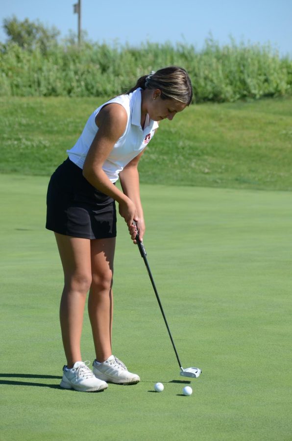 PRACTICING THE PUTT Lining up the shot, Alexis Schmidt, junior, warms up before the match. 
