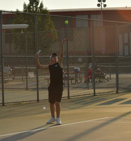 MAKING A RACKET Tossing the ball in the air, Jack Morton, freshman, prepares to serve.
