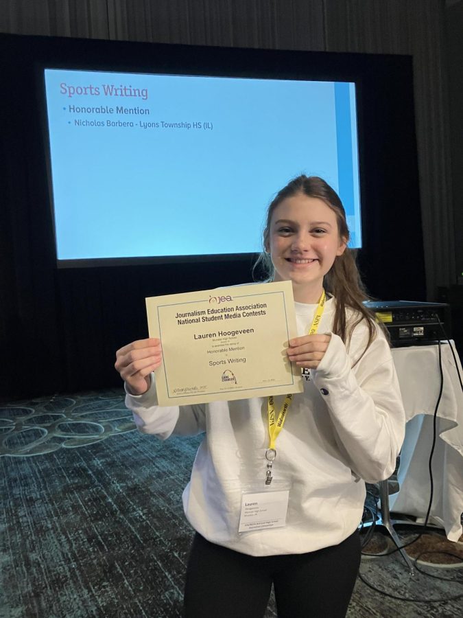 MAKING HER MARK Standing in front of the awards display at the St. Louis National Student Media Convention, Lauren Hoogeveen, junior and story editor, receives an Honorable Mention in Sports Writing. 