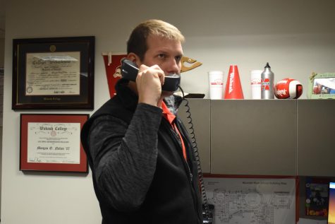 ROLL STANGS As he makes the morning announcements, Mr. Morgan Nolan, principal, watches students scuttle in the doors late through his office window.