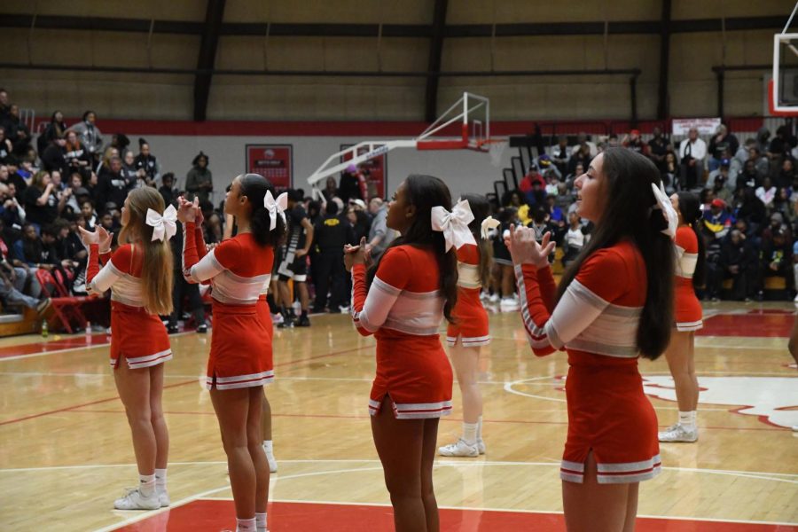 IN A CHEERFUL MOOD Standing in formation, from left to right,  sophomores Scarlett Mrvan and Nadia Pierre-Auguste and juniors Morgan Samuel and Kiki Petrovic prepare to cheer at the Boys’ Basketball Sectional game. “I love performing at the games,” Petrovic said. “The energy of the student section creates an exciting environment and helps boost overall morale.”