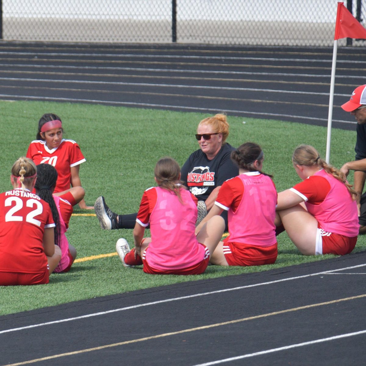 LETS TALK Sitting together, the girls varsity soccer team and Coach Valerie Pflum run through plays together after a loss. The team makes it a point to review their performance for improvement in future games. 
