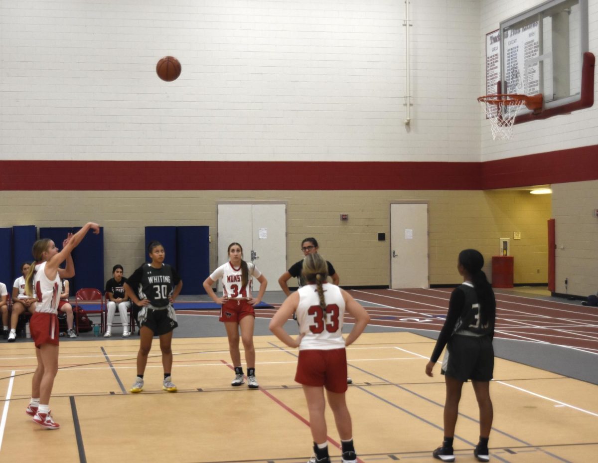 TAKING THE SHOT Throwing the ball into the air, Addie Smitka, sophomore, takes a free throw shot while a Whiting player and Elena Dovellos, freshman, watch. At the Nov. 12 Crown Point tournament, the team won their first game 31-28 against Whiting, but lost their second game 20-36 against Lebanon. 