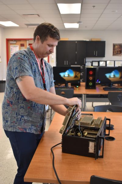 PIECE BY PIECE Bringing in a power box to the PLTW classes, Mr. Josh Collier, engineering teacher, disassembles it to show the wiring compartments. 