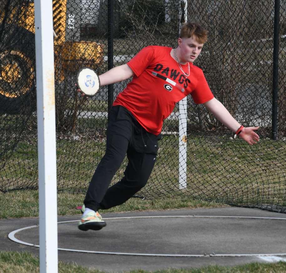 BACK IN THE SANDBOX At the back of the track field, DJ Certa, junior, winds up in form to practice throwing the discus as far as possible. (photo by. 