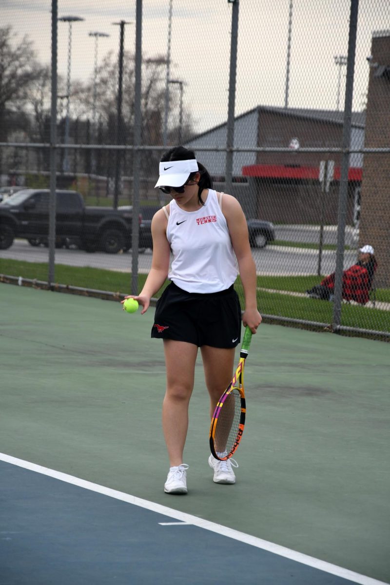 STEPPING FORWARD Preparing to serve to her Crown Point opponent, Claire Han, junior, bounces the ball. This was her first match of her junior year  season. 