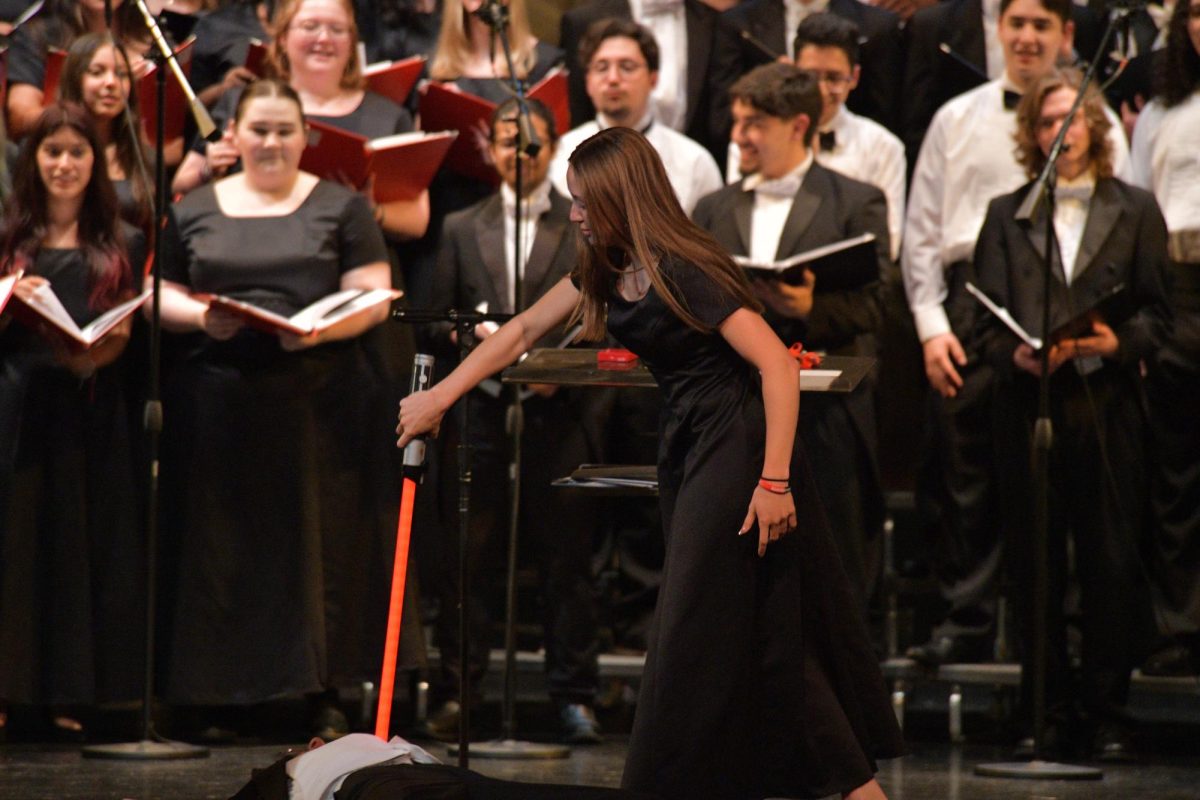 SENIOR SLAY Holding a lightsaber, Addison Dzurovcik, senior, stabs Jovi Savaglio, junior, during the last choir concert May 9. The title was “Duel of the Fates,” which included a lightsaber battle mid-performance.