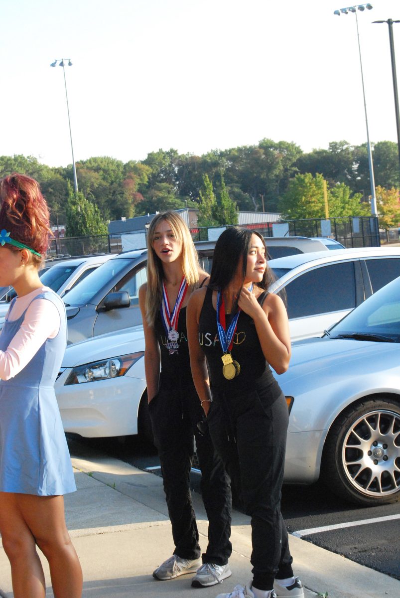 MEDALS ON MEDALS Standing in the parking lot before school, juniors Laila Collard and Nadia Ornelas watch others take photos.