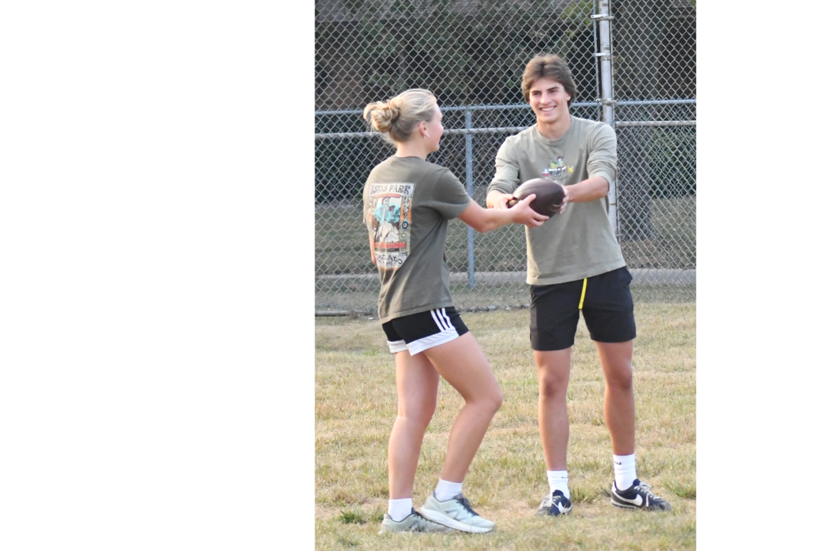 GAME PLAN On the field, junior Grace Schirz gives the football to senior and coach Henry Adams at Powderpuff practice. At the practice, two days before the game, they discussed positions and practiced plays to use against the seniors. 