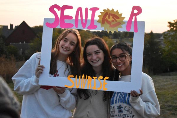 SMILE BRIGHT Posing for a photo, seniors Grace Peters, Savannah Neutzel and Jiselle Ruiz hold up a sign. Neutzel made the sign for fun photo options for seniors at senior sunrise “I am not creative, but I thought if I would use it then other people would too,” Neutzel said. 