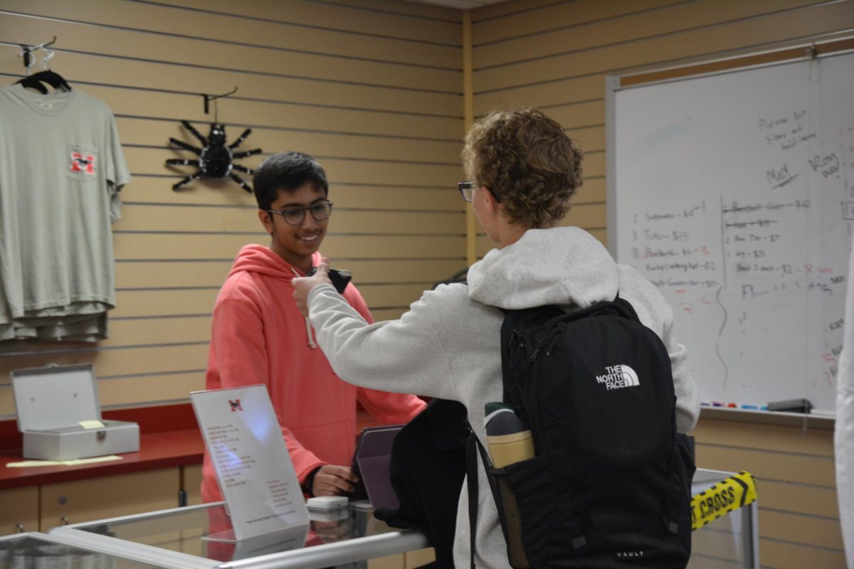 STOP TO SHOP Purchasing merchandise after C lunch, junior Carson Poulston hands sophomore Raunav Perinchery his credit card. “It is very nice to buy clothes at the Horseshoe,” said Poulston. “It is easy to access during lunch.” 