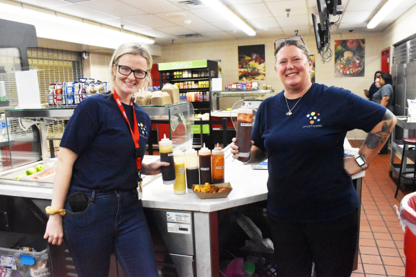 BEHIND THE LINES Holding different sauces, lunch staffers pose with the new chicken wings added to the Create line. This year the lunch room has introduced a new high-protein lunch option for students and staff. 