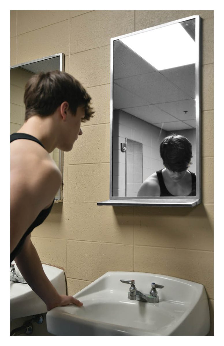 IDENTITY IN REFLECTION Hunched over a sink in the school bathroom, junior Nolan Gill looks into a mirror where his reflection is distorted. According to Parents.com “60% of young men between the ages of 16-25 regularly consume content from at least one masculinity influencer.” 