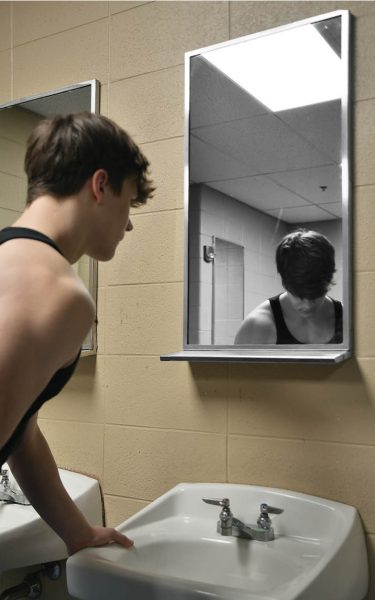 IDENTITY IN REFLECTION Hunched over a sink in the school bathroom, junior Nolan Gill looks into a mirror where his reflection is distorted. According to Parents.com “60% of young men between the ages of 16-25 regularly consume content from at least one masculinity influencer.” 